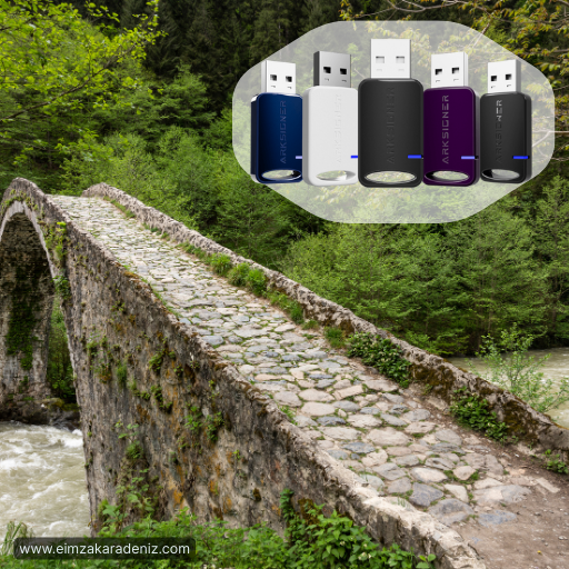 Rize’de açık havada e-imza kurulum desteği alan bir kişinin laptopuna ARKSIGNER e-imza cihazı takılırken çekilmiş tanıtım görseli. Arka planda büyük RIZE yazısı ve yeşil dağ manzarası görülüyor.